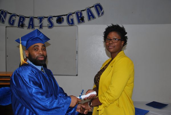Floyd A. receives his diploma from Ms. Brooks, Education Manager
