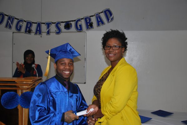 Resident Kaseem J. receives his diploma from Ms. Brooks, Education Manager