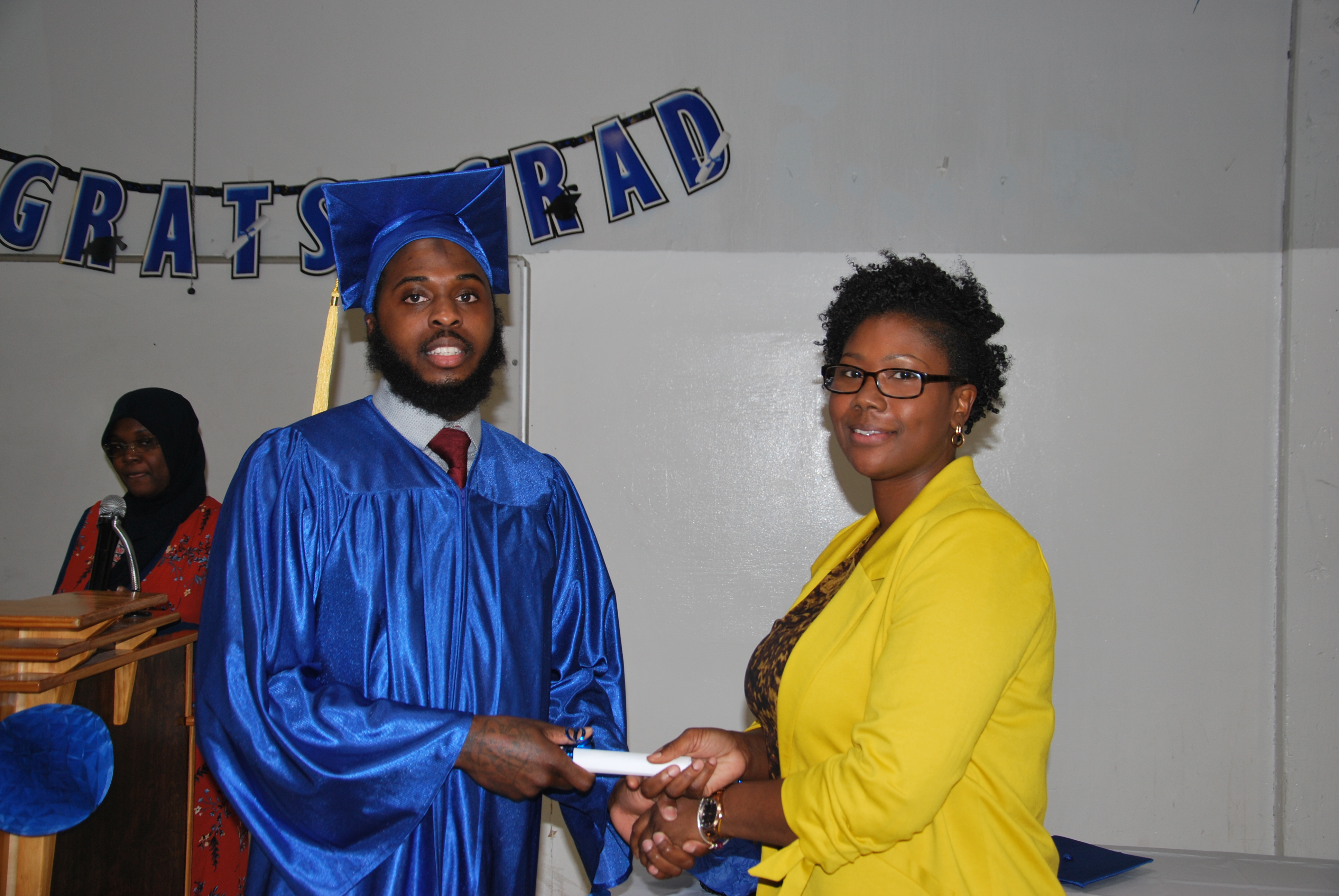 Resident Whanyah D. receives his diploma from Ms. Brooks, Education Manager