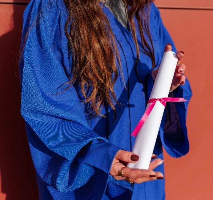 Woman in graduation gown holding diploma, representing Coeur d’Alene reentry program graduate